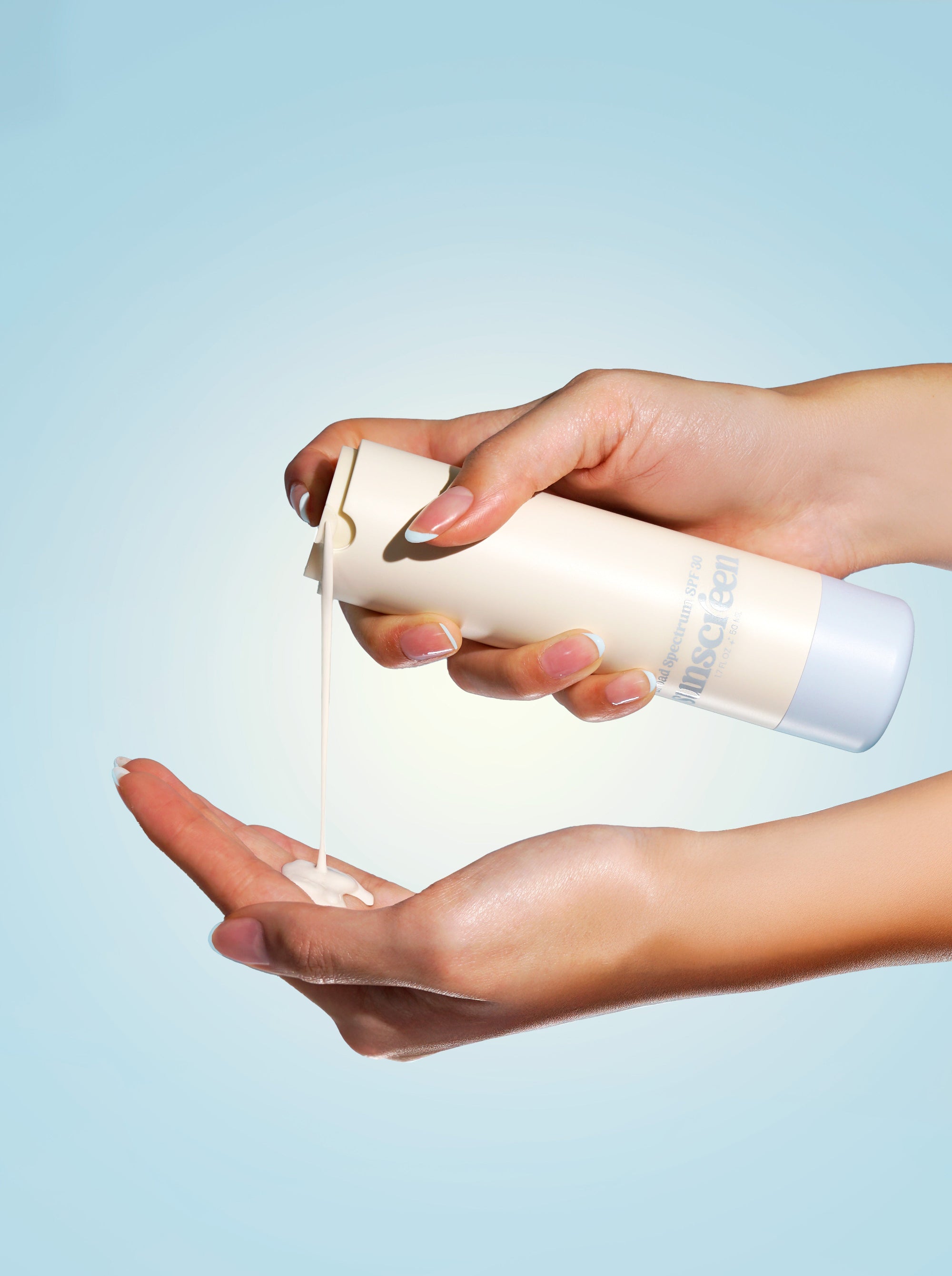 Girlyish Mineral Sunscreen SPF 30 being poured into a hand with a blue background