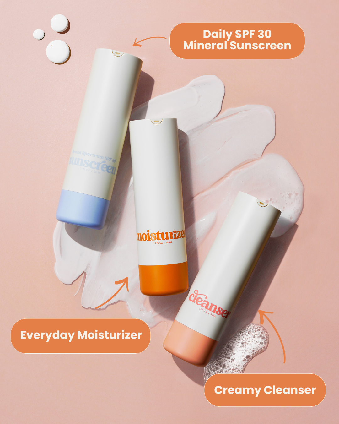 Girlyish cleanser, moisturizer, and sunscreen laying on top of the skincare textures